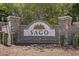 A brick community sign for SAGO with an attractive floral design sits amidst green bushes and foliage at 610 Cocas Dr., Myrtle Beach, SC 29579