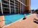 Large outdoor swimming pool with ample lounge chairs and a brick pool deck at 6900 N Ocean Blvd. # 1034, Myrtle Beach, SC 29579