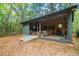 Rustic cabin with a covered porch surrounded by lush greenery, showcasing outdoor living space at 70 Izard Pl., Georgetown, SC 29440