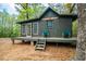 Quaint cabin-style home featuring a front porch with chairs and a charming setting among the trees at 70 Izard Pl., Georgetown, SC 29440