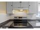 Close up on a modern electric stove with a hood vent and white cabinets at 8404 Bloomwood Dr., Myrtle Beach, SC 29588