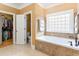 Bathroom featuring a soaking tub, neutral tile, and a closet at 9 Gasparilla Circle, Murrells Inlet, SC 29576