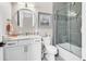 Well-lit bathroom with a vanity, toilet, round mirror, and a shower-tub combo behind a glass door at 9407 Venezia Circle, Myrtle Beach, SC 29579