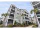 Exterior of a multilevel condo building featuring screened-in porches, landscaping, and palm trees at 126 Ella Kinley Circle # 401, Myrtle Beach, SC 29588