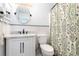 Updated bathroom with an oval mirror, vanity, tile backsplash, and patterned shower curtain at 1310 N Waccamaw Dr. # 211, Garden City Beach, SC 29576