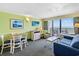 A well lit living room with blue furniture, dining table, TV, and ocean view balcony at 3000 N Ocean Blvd. # 729, Myrtle Beach, SC 29577