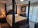 Bedroom with four-poster bed, wood floor, and a window with natural light at 4701 N Kings Hwy. # 19, Myrtle Beach, SC 29579