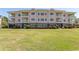 Exterior of condos with green lawn, pink siding and white railings on upper decks at 4823 Orchid Way # 2-203, Myrtle Beach, SC 29577