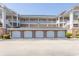 Exterior view of garages beneath condo featuring brick facade and white garage doors at 4823 Orchid Way # 2-203, Myrtle Beach, SC 29577