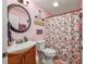 Pink bathroom with floral shower curtain, round mirror, and wooden vanity at 4520 Hedrick St., North Myrtle Beach, SC 29582