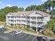 Multi-story condo building with white balconies, brick accents, and parking in a landscaped community at 5750 Oyster Catcher Dr. # 714, North Myrtle Beach, SC 29582