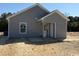 Rear exterior showcasing neutral siding, a window and a back door with storm doors and landscaping potential at 8050 Mill Pond Rd., Galivants Ferry, SC 29544