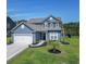 Charming two-story home featuring blue siding, a well-manicured lawn, and a two-car garage at 897 Wild Leaf Loop, Conway, SC 29526