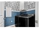 Modern laundry room with black washer and dryer, stylish wallpaper, and blue wainscoting at 897 Wild Leaf Loop, Conway, SC 29526