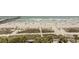 Overhead view of the beach with sand, ocean, grassy dunes, and a wooden pier at 1200 N Ocean Blvd. N # 905, Myrtle Beach, SC 29577
