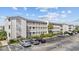Low-angle view of a multi-story condo with white balconies, lush landscaping, and ample parking space at 1919 Spring St. # 36A, North Myrtle Beach, SC 29582