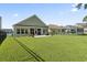 Spacious backyard featuring lush green grass, a fence, a home with a porch, and houses in the neighborhood at 230 Palmetto Green Dr., Longs, SC 29568