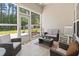 Comfortable screened porch featuring wicker furniture, neutral colors, and a view of the wooded backyard at 230 Palmetto Green Dr., Longs, SC 29568