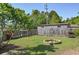 Large wooden shed in a fenced backyard, complemented by lush greenery and a cozy brick fire pit at 4196 E Highway 319, Conway, SC 29526