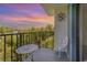 Balcony with a table and chair offering beautiful views of lush greenery and vibrant sunset skies at 5001 Little River Rd. # 501E, Myrtle Beach, SC 29577