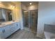 Modern bathroom with double vanity, quartz countertop, a glass-enclosed shower and tub with grey stone-look tile surround at 553 Honeyhill Loop, Conway, SC 29526
