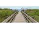 Picturesque wooden boardwalk leads to a serene beach with gentle waves and lush vegetation at 5600 North Ocean Blvd. # B-3, North Myrtle Beach, SC 29582