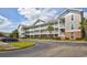 Exterior view of condo with white railings, stairs, parking, and beautiful landscaping at 5750 Oyster Catcher Dr. # 1135, North Myrtle Beach, SC 29582