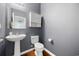 This powder room features a pedestal sink, white storage cabinet, and modern gray walls at 650 Woodman Dr., Conway, SC 29526