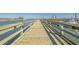 Water view of a wooden fishing pier stretching out to a river with boats moored along the side at 948 Jackline Place # 201, Murrells Inlet, SC 29576