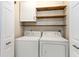 Well-lit laundry room featuring a white washer and dryer, wooden shelves, and white cabinets at 237 Chesapeake Ln., Murrells Inlet, SC 29576