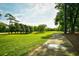Picturesque golf course with a paved path, framed by mature trees and a clear blue sky at 273 Golden Bear Dr. # F3, Pawleys Island, SC 29585