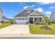 Charming single-Gathering home with a well-manicured front lawn, flower bed, and inviting front porch at 296 Switchgrass Loop, Little River, SC 29566