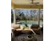 Covered patio with comfortable seating offers a serene view of the fenced pool area surrounded by mature trees at 4016 Atalaya Pl., Myrtle Beach, SC 29579
