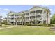 Beautiful condo building with white balconies, palm trees, and manicured lawn at 5801 Oyster Catcher Dr. # 912, North Myrtle Beach, SC 29582