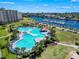 Aerial view of a resort-style pool with palm trees, a nearby building, a marina, and a waterway at 5801 Oyster Catcher Dr. # 912, North Myrtle Beach, SC 29582