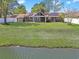 Spacious backyard view showing a brick home, green lawn, and waterfront features, perfect for outdoor enjoyment at 584 Circle Dr., Surfside Beach, SC 29575