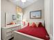 Cozy bedroom with white furniture, red bedding, decorative pillows, and a beach-themed painting at 6001-8050 S Kings Hwy., Myrtle Beach, SC 29575