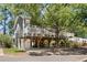 Elevated home with parking, entertainment space, and a white fenced porch, shaded by a mature tree at 6001-8050 S Kings Hwy., Myrtle Beach, SC 29575