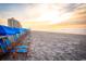 Stunning beachfront view with rows of blue beach chairs under a vibrant, colorful sunrise at 9547 Edgerton Dr. # 702, Myrtle Beach, SC 29572