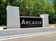 Elegant community entrance sign for Arcadia, framed by white brick pillars and lush greenery at 1056 Laconic Dr., Myrtle Beach, SC 29588