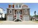 Stunning three-story home featuring stone accents, dual garages, and welcoming entry stairs at 133 Serenity Point Dr., Little River, SC 29566