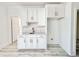 A modern wet bar featuring white cabinetry, marble countertops, and a unique backsplash design at 133 Serenity Point Dr., Little River, SC 29566
