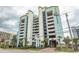Modern condo building with a parking garage, beautiful landscaping, and tropical palm trees at 6804 Ocean Blvd. N # 625, Myrtle Beach, SC 29572
