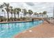 Long outdoor pool with a small bridge, sun loungers, and palm trees at 6804 Ocean Blvd. N # 625, Myrtle Beach, SC 29572