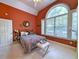 A bedroom with a large window, queen bed, and red accent wall provides a welcoming, tranquil space at 710 Masters Dr., Pawleys Island, SC 29585