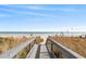 Scenic boardwalk leading to a sandy beach with ocean views under a clear blue sky at 7100 N Ocean Blvd. # 405, Myrtle Beach, SC 29572