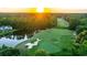 Aerial view of golf course at sunset featuring lush green fairways, a serene pond, and mature trees at 10 Logan Berry Ct. # H, Murrells Inlet, SC 29576
