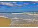 Calm beach scene with gentle waves and sandy shoreline under a bright, partly cloudy blue sky at 110 Portsmith Dr. # 8, Myrtle Beach, SC 29588