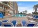 Outdoor pool area with lounge chairs, palm trees, and a view of the building and blue sky at 2711 S Ocean Blvd. # 621, North Myrtle Beach, SC 29582