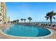 Large outdoor pool with lounge chairs, palm trees, and views of the ocean and clear blue sky at 2711 S Ocean Blvd. # 621, North Myrtle Beach, SC 29582